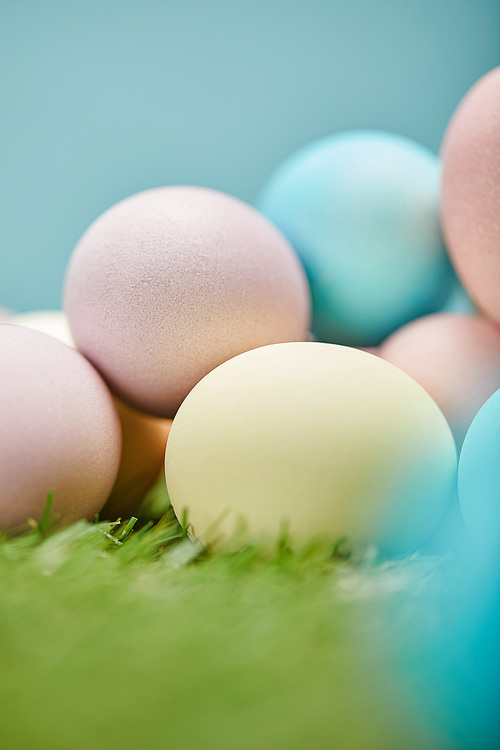 close up of painted easter eggs on grass and on blue background