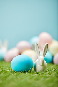 selective focus of painted easter eggs and toy rabbit on grass with copy space