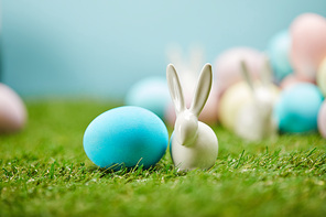 selective focus of painted easter eggs and toy rabbits on grass with copy space