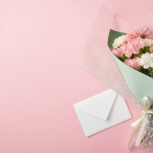 beautiful tender flower bouquet and white envelope isolated on pink background