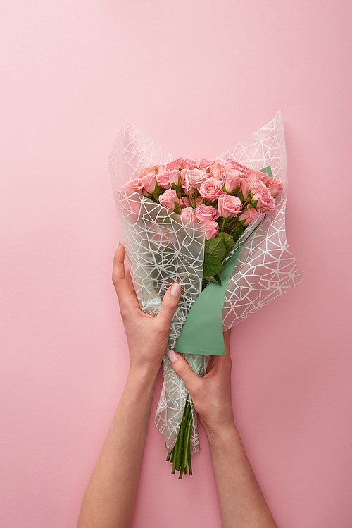 cropped shot of woman holding bouquet of beautiful roses isolated on pink