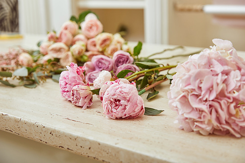 selective focus of pink roses and peonies on surface