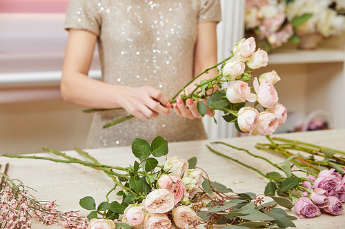 partial view of florist making bouquet of roses and peonies