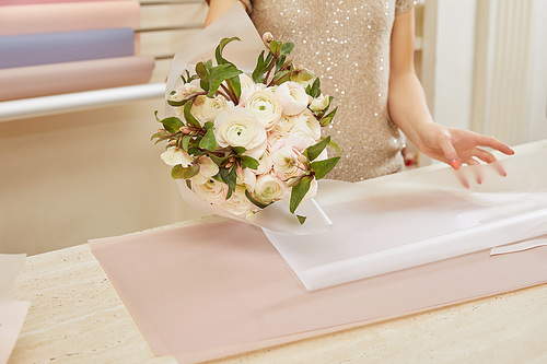 partial view of florist wrapping bouquet of white peonies at workspace