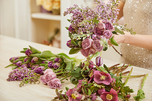 selective focus of florist making bouquet of tulips, peonies and lilac