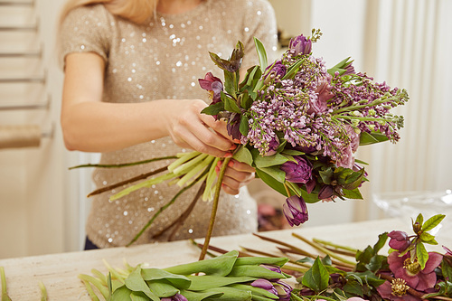 florist making bouquet of tulips, peonies and lilac at workspace