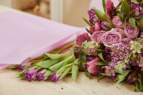 selective focus of purple tulips, peonies and lilac on table