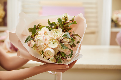 partial view of florist holding bouquet of white peonies at workplace