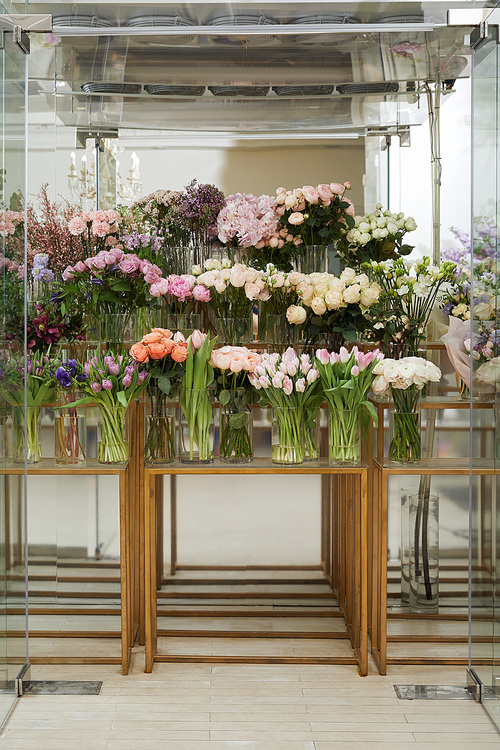 roses, tulips and peonies in vases on glass tables