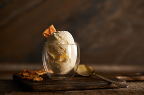 selective focus of delicious ice cream with piece of waffle in glass on wooden cutting board