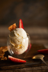 selective focus of delicious ice cream with strawberry and piece of waffle on cutting board