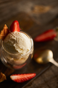 selective focus of delicious ice cream with piece of waffle and strawberries in glass