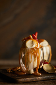 delicious ice cream with caramel in glass on wooden chopping board