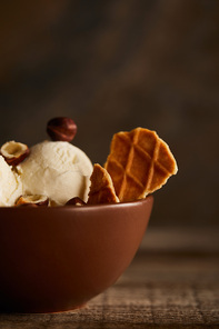 selective focus of delicious ice cream with pieces of waffle and hazelnuts in bowl