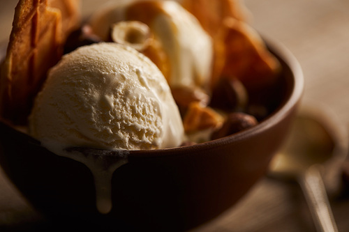 selective focus of of delicious melting ice cream in bowl with pieces of waffle