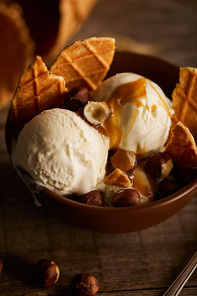 delicious ice cream with pieces of waffle, caramel and hazelnuts in bowl