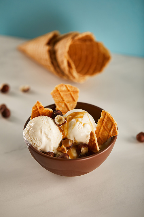 bowl of delicious ice cream with caramel, hazelnuts and pieces of waffle