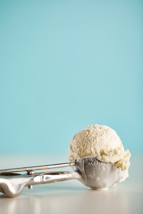 ice cream scoop in metal spoon on blue with copy space