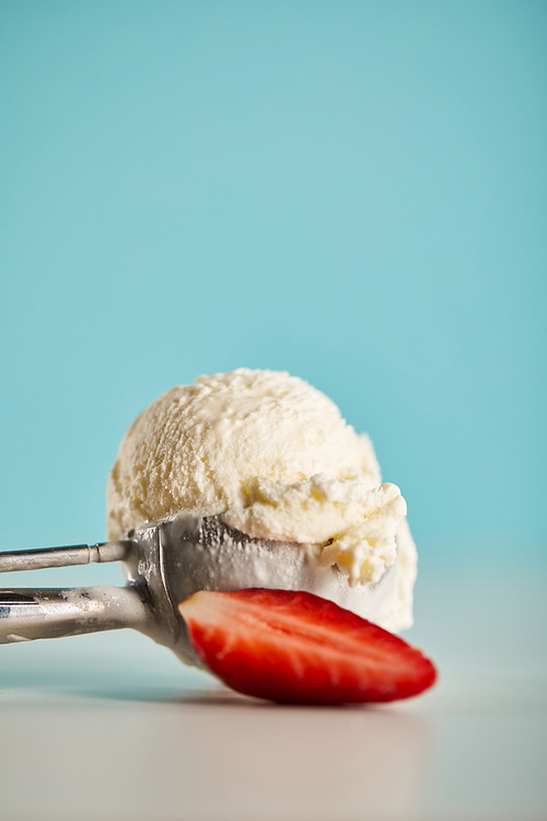 scoop of ice cream in spoon and strawberry on blue with copy space