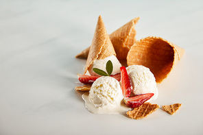 waffle cones and delicious melting ice cream with strawberries on grey table with copy space