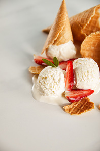 waffle cones and delicious melting ice cream with strawberries on grey