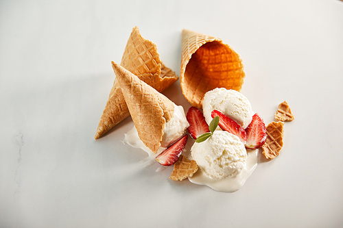 waffle cones and melting ice cream with strawberries on grey