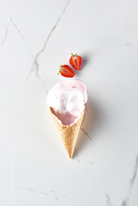 top view of delicious ice cream in waffle cone near strawberries on marble grey background