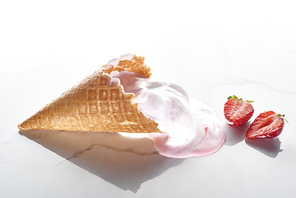 delicious ice cream in waffle cone near strawberries on marble grey background