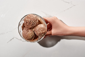 cropped view of woman holding delicious chocolate ice cream in bowl on marble grey background