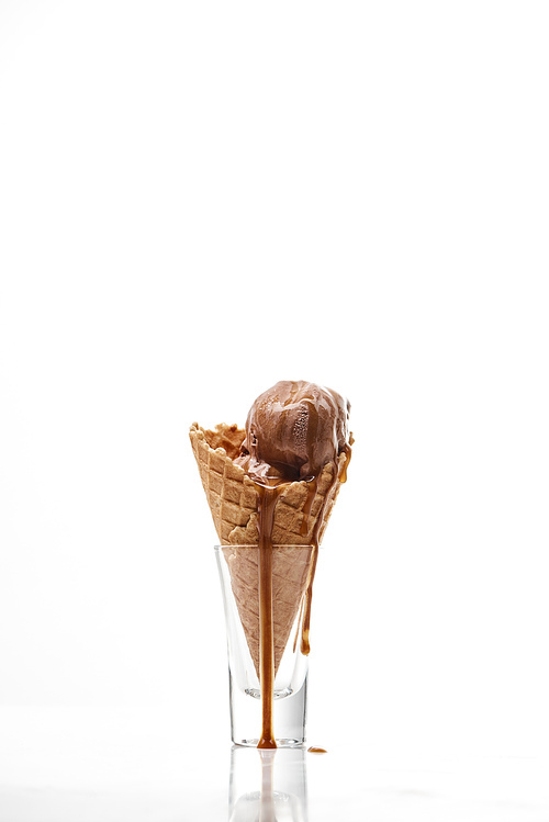 delicious sweet chocolate ice cream with melted dripping chocolate in crispy waffle cone isolated on white
