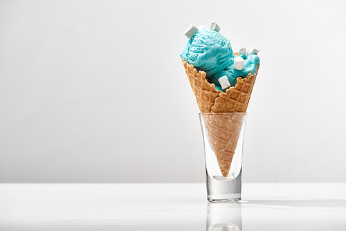 delicious sweet blue ice cream with marshmallows in crispy waffle cone isolated on grey