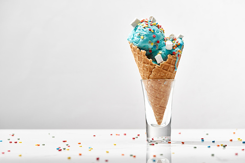 delicious sweet blue ice cream with marshmallows and_sprinkles in crispy waffle cone isolated on grey