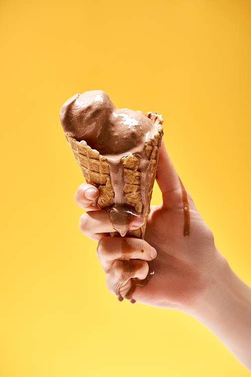 cropped view of woman holding delicious melted chocolate ice cream in crispy waffle cone isolated on yellow