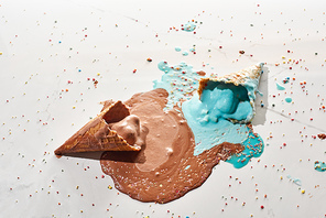 top view of delicious melted chocolate and blue ice cream in waffle cones on marble grey background with sprinkles
