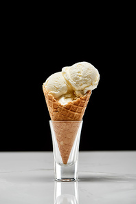 delicious vanilla ice cream in crispy waffle cone isolated on black