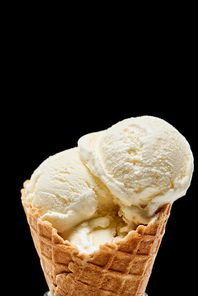 close up view of delicious vanilla ice cream in crispy waffle cone isolated on black