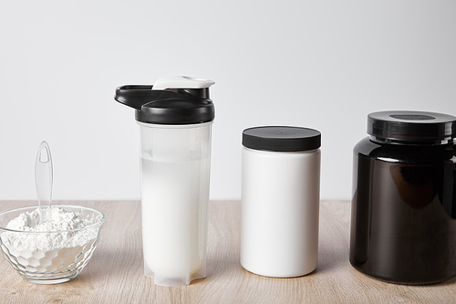 protein shake in sports bottle near jars isolated on grey