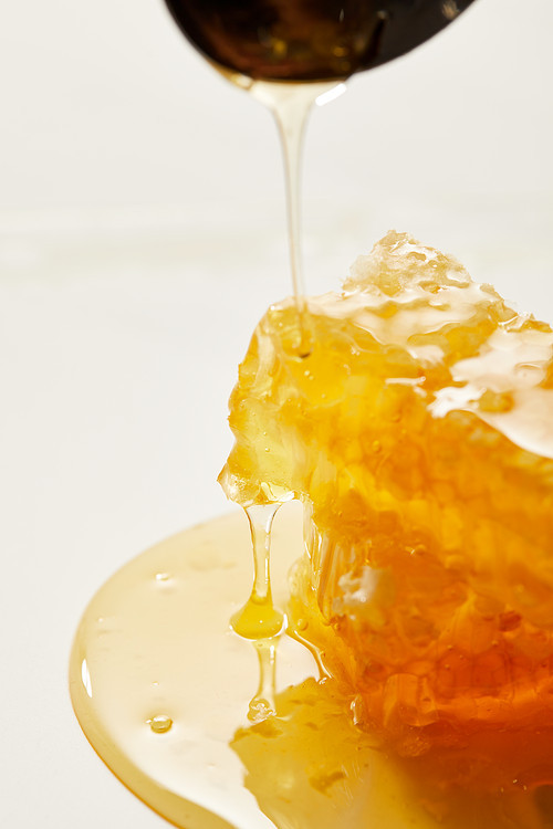 close up view of beeswax and pouring honey process on white backdrop