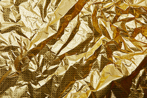 full frame of shiny crumpled golden wrapping paper as background