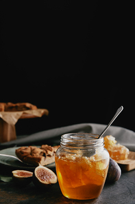 close up view of glass jar with honey| figs and baked pie on dark surface