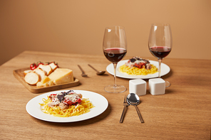 plates of tasty pasta with red wine in glasses on wooden table