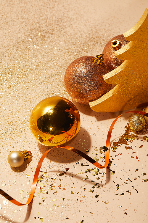 high angle view of christmas balls| decorative christmas tree| wavy ribbon and glitter on tabletop