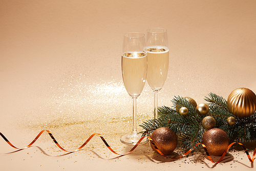 glittering christmas balls| pine branch and glasses of champagne on tabletop