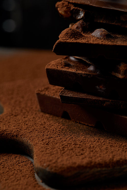 close-up view of delicious chocolate pieces with nuts and cocoa powder on chopping board