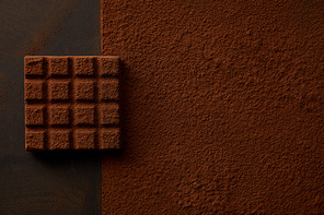 top view of delicious brown cocoa powder and tasty chocolate on black background