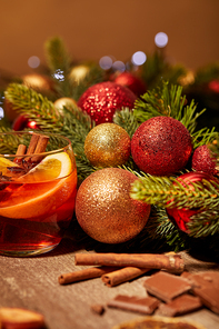 close up view of mulled wine drink in glass| chocolate and pine tree with christmas toys on wooden surface