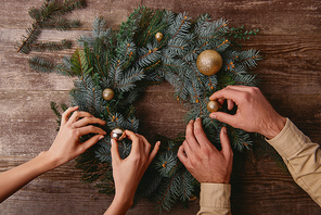 cropped image of couple decorating christmas fir wreath together