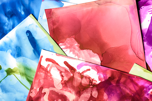 blue| red and green splashes of alcohol inks on paper sheets as abstract background