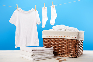 laundry basket| pile of clean soft towels and white clothes hanging on clothesline on blue