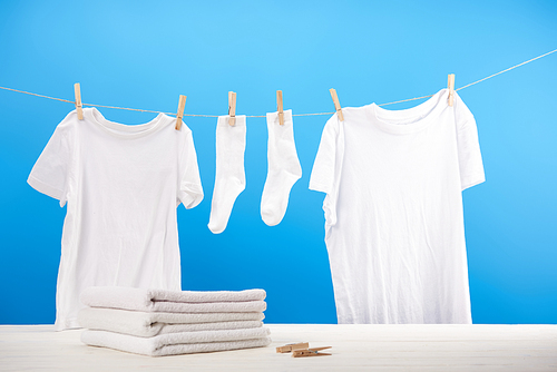 pile on clean towels| clothespins and white clothes hanging on rope on blue